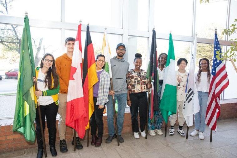 在去年的国际周期间，学生们站在各自国家的国旗旁.